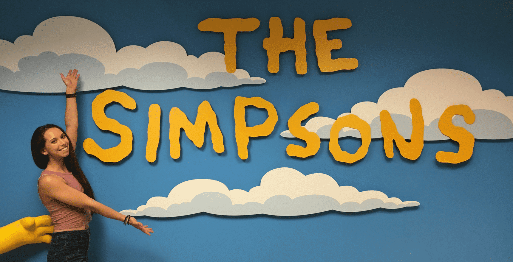 Chloe Dejong posing in front of The Simpsons installation